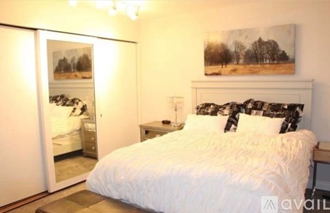 A bedroom with a large bed and a painting on the wall.