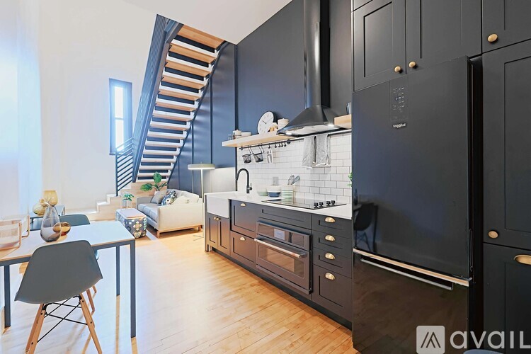 A kitchen with black cabinets and a wooden floor.