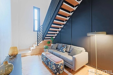 A living room with a grey couch and a staircase.