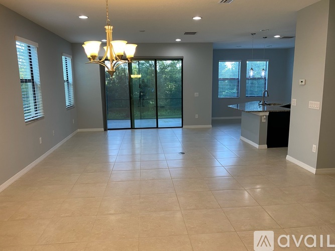 A spacious room with tiled flooring and a chandelier hanging from the ceiling.