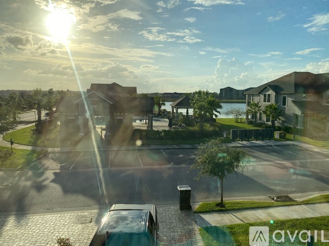 A sunny day in a residential area with houses and a car parked on the street.