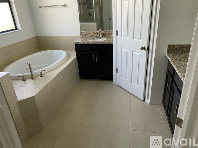 A bathroom with a tub, sink, and a door.