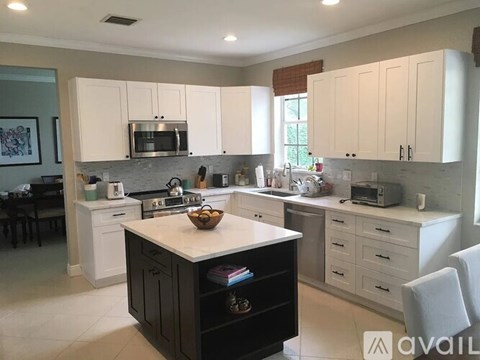 A kitchen with white cabinets and a black island.