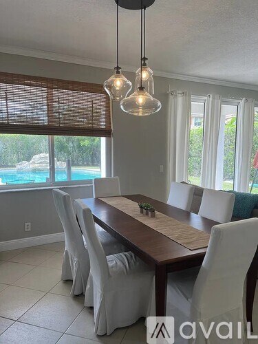 A dining room with a wooden table and white chairs.