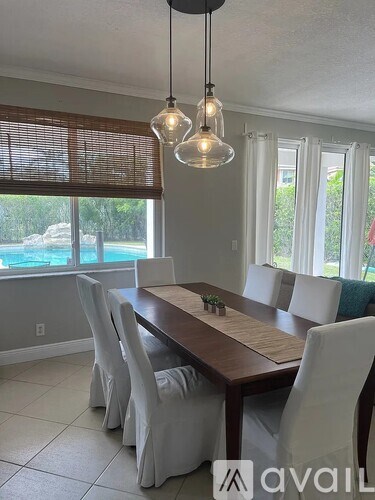A dining room with a wooden table and white chairs.