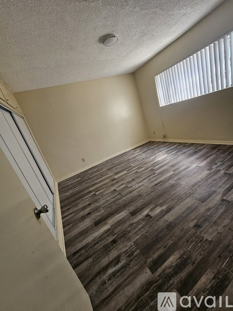 A room with wooden flooring and a window with blinds.
