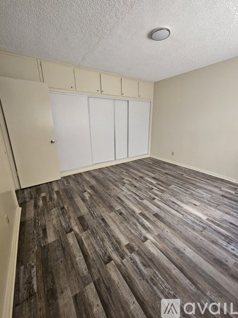 A room with wooden flooring and white cupboards.
