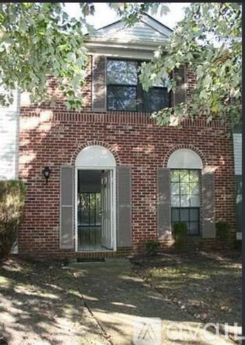 A red brick house with a white door and windows.