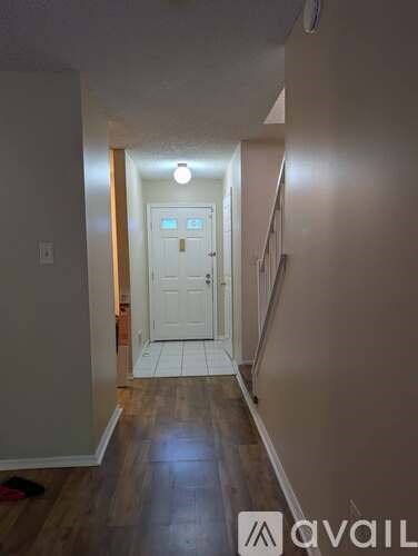 A hallway with a white door and wooden floors.