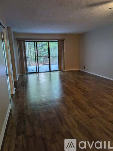 A room with wooden floors and a sliding glass door leading outside.