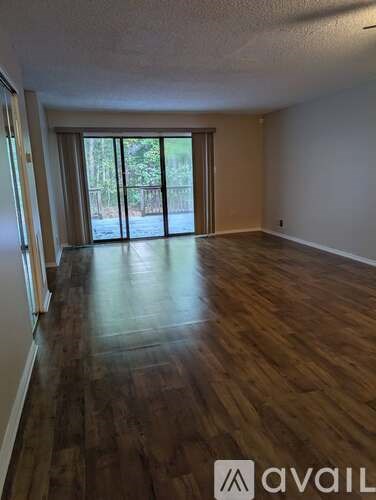 A room with wooden floors and a sliding glass door leading outside.