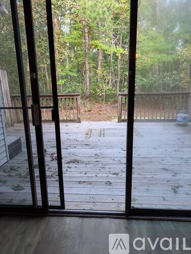 A view from inside a room looking out through a glass door to a deck with a railing.