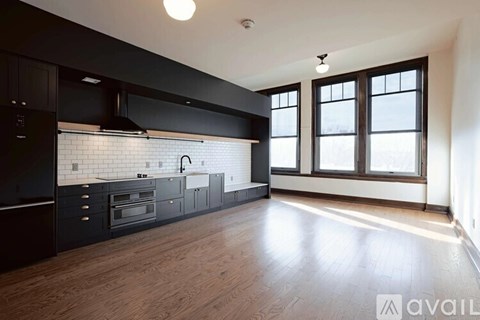 A kitchen with black cabinets and a wooden floor.
