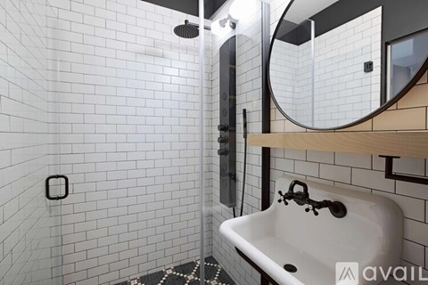 A bathroom with a white tiled shower and a white sink.