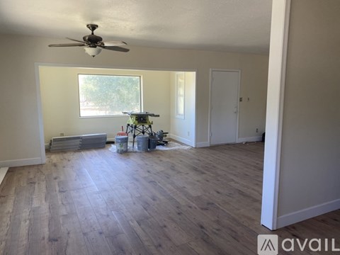 A room with a ceiling fan and wooden flooring.