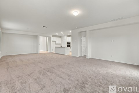 A spacious living room with a carpeted floor and white walls.