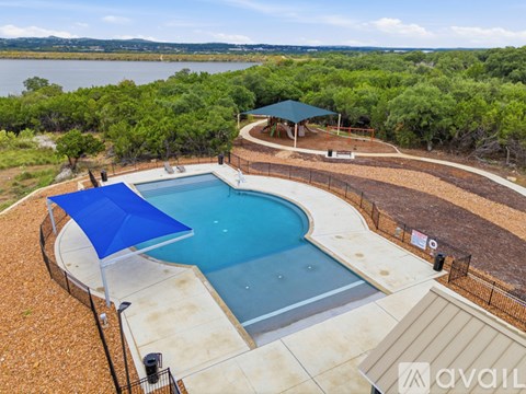 A pool with a blue umbrella and a view of a lake.