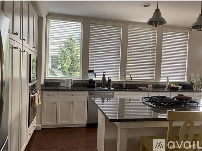 A kitchen with white cabinets and a black countertop.