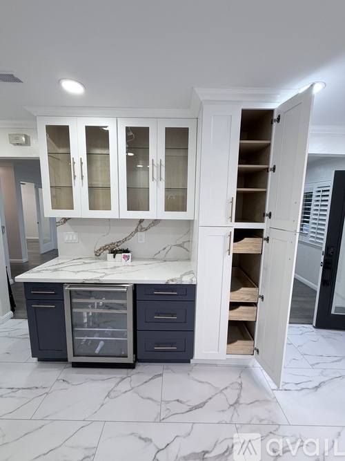 A kitchen with white cabinets and a marble countertop.