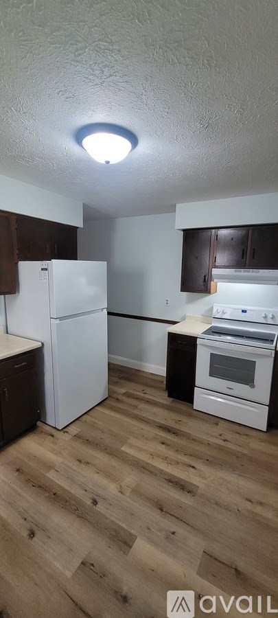 A kitchen with a white refrigerator and wooden floors.