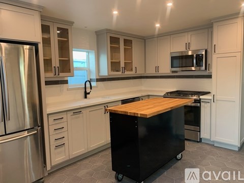 A kitchen with white cabinets and a black island.