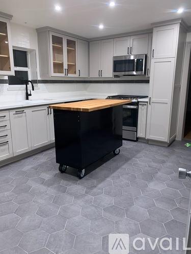 A kitchen with a black fridge on wheels.