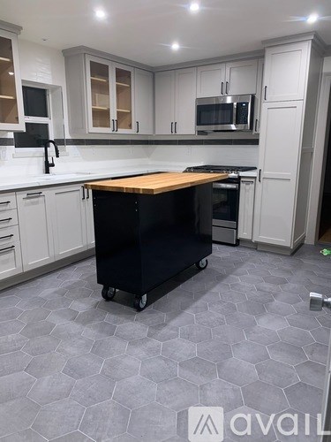 A kitchen with a black fridge on wheels.