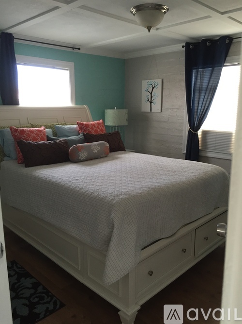 A bedroom with a white bed and a painting on the wall.