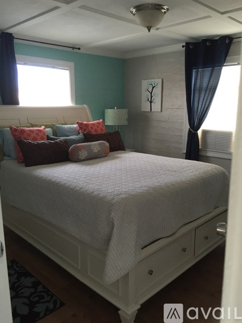 A bedroom with a white bed and a painting on the wall.