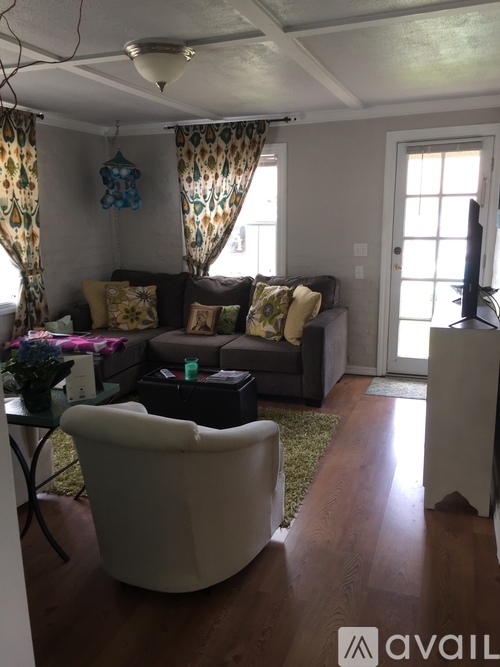 A living room with a white chair and a brown couch.