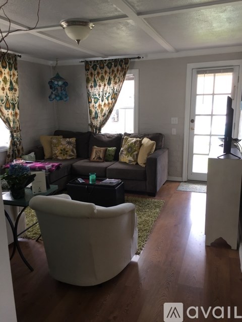 A living room with a white chair and a brown couch.