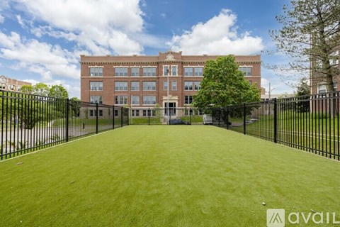 A large grassy area in front of a brick building with a black fence.