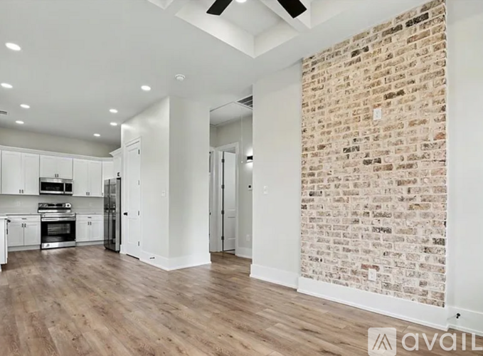 A kitchen with a brick wall and wooden floors.