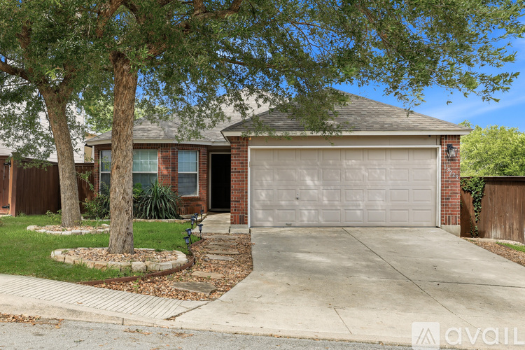A house with a tree in front and a driveway leading to a garage.
