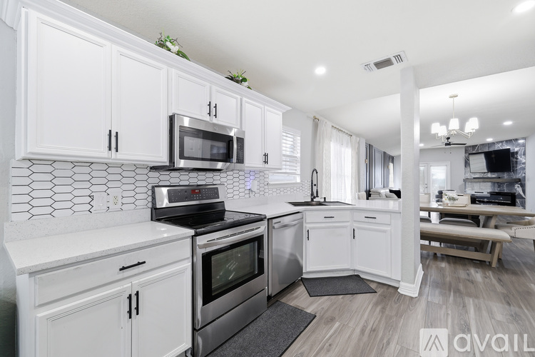 A modern kitchen with white cabinets and stainless steel appliances.