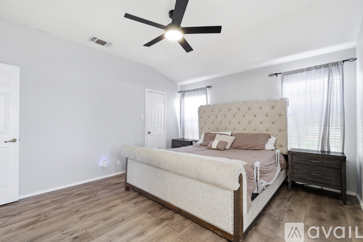 A bedroom with a large bed and a ceiling fan.