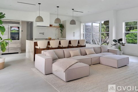 A modern living room with a large sectional sofa and pendant lights.