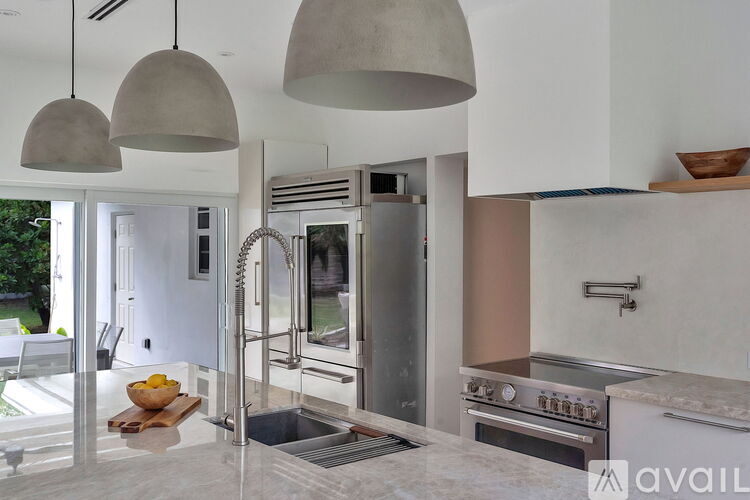 A modern kitchen with a stainless steel refrigerator and a marble countertop.