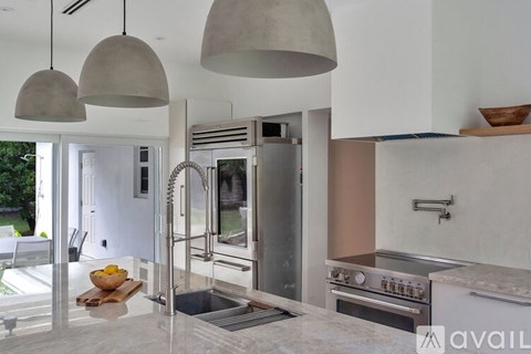 A modern kitchen with a stainless steel refrigerator and a marble countertop.