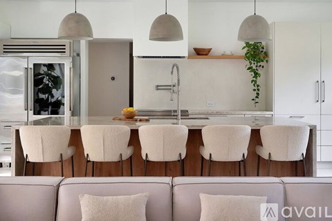 A modern kitchen with a white interior and a grey sofa with white cushions.