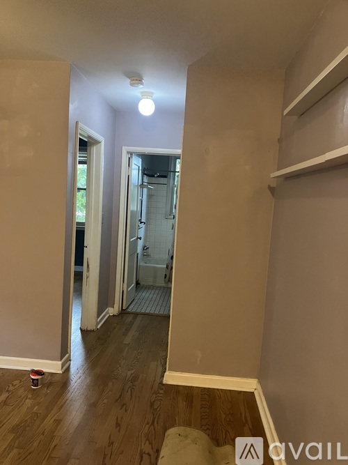 A room with a wooden floor and a white door leading to a bathroom.