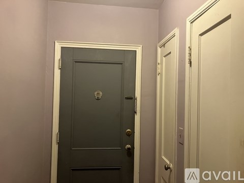 A grey door with a silver handle is in a room with a white door to the right.