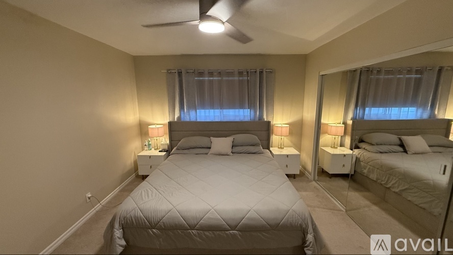 A bedroom with two beds, both with white bedspreads and pillows, and a ceiling fan.