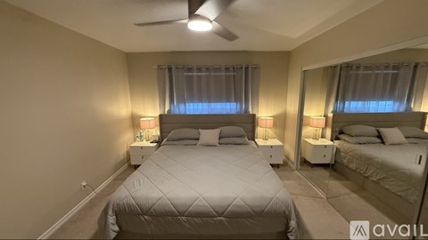 A bedroom with two beds, both with white bedspreads and pillows, and a ceiling fan.