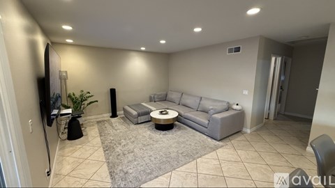 A living room with a grey couch, a white coffee table, and a flat screen TV.