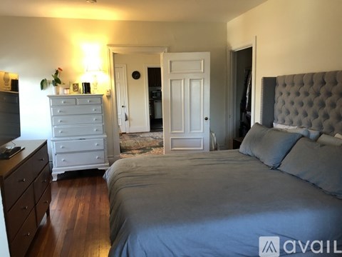 A bedroom with a large bed and a dresser with a TV on top.