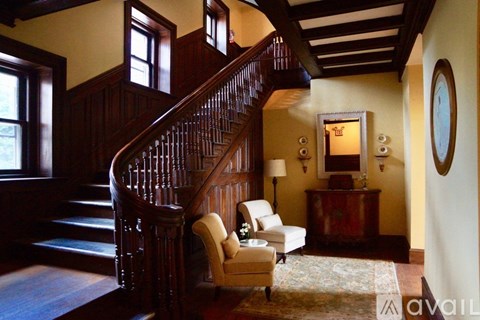 A wooden staircase with a carpeted floor and a chair with a white cushion.