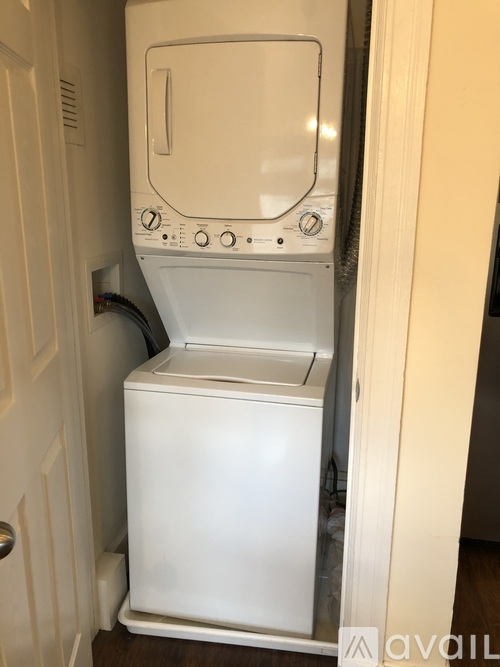 A white dishwasher is in a narrow space between a door and a wall.