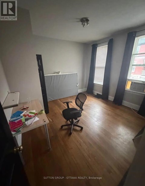 A room with a desk, chair, and a window with blinds.