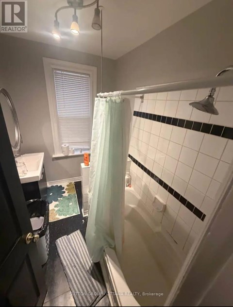 A bathroom with a white shower curtain and a black and white tile wall.